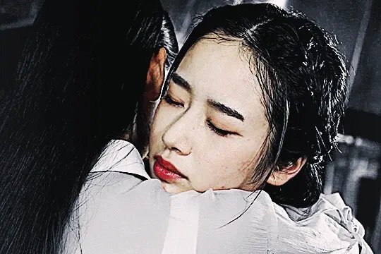 GIF of nayuta's face as she leans on and hugs rinne who holds her up. nayuta has a solemn expression. the colors are mainly cool toned but the red tones pop a bit