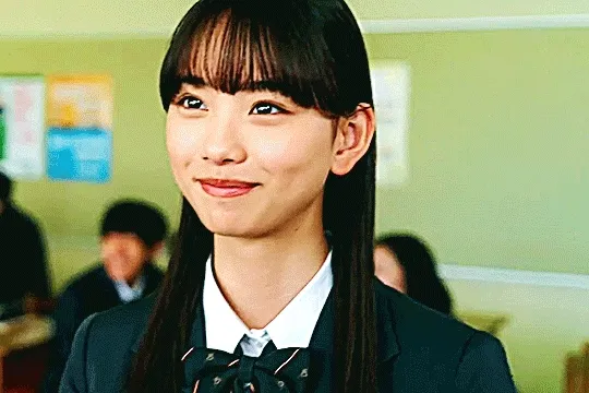 kudou rinne in kamen rider gotchard. she's in a classroom looking at an off-camera houtarou, smiling brightly and then nodding, as her smile grows in joy