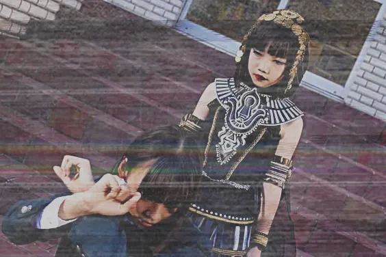 screen cap from kamen rider gotchard of atropos smiling and menacing rinne from behind who has her head turned to the side and her arms up in a self defense pose. the image is edited to be super glitch-y with tears and distortions that resemble visual distortions of a VHS tape, with dark and rainbow bars, black and white rips, and lots of visual noise, all very washed out