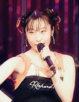 dambara ruru singing and dancing with her group as they perform more mi amore. the gif is very flashy and glowing, with pseudo-sparkle effects all over