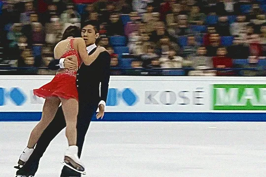 cong han holds wenjing sui as she lays atop him and he skates standing up, and she slides her hand down as she leans on him